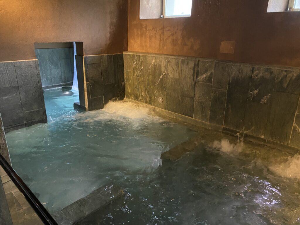 Bassin thermal semi-intérieur avec jets d’eau, entrée vers l’extérieur